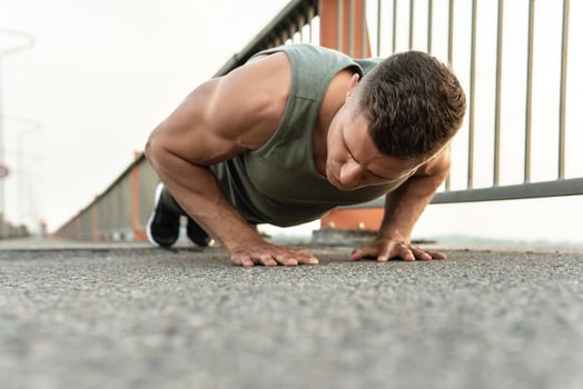 Muscular man is doing push-ups during calisthenic workout on a street photo