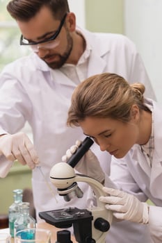 Two scientist colleagues are using microscope during research in a laboratory photo