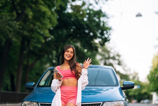 Woman using mobile phone near car at the street photo
