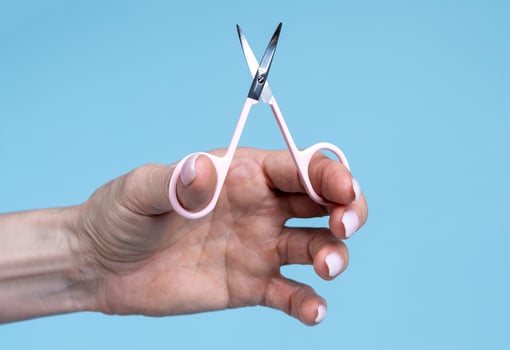 female hand holding scissors isolated on  blue background photo