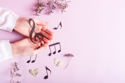 Paper musical clef in children's hands and paper notes on pink. Music education. Top view. photo