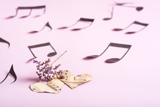 The concept of love for music. Two paper hearts, dry flowers and notes around on a pink background photo