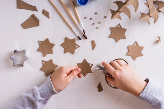 Children's hands cut out stars from cardboard for DIY Christmas handmade decorations. Top view. photo