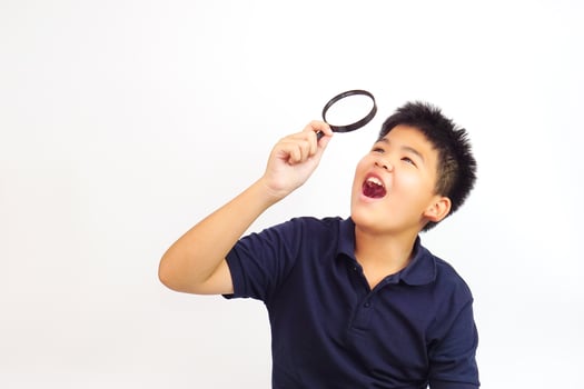 Boy holding a magnifying glass on white background. Knowledge, research and explore concept. photo