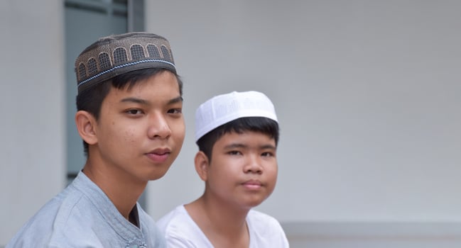Portrait asian muslim or islamic boys sitting with muslim boys in a row to pray or to do the religious activity, soft and selective focus. photo