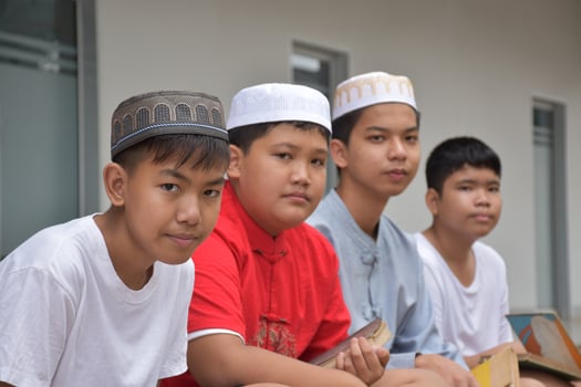 Asian muslim or islamic boys sitting with muslim boys in a row to pray or to do the religious activity, soft and selective focus. photo