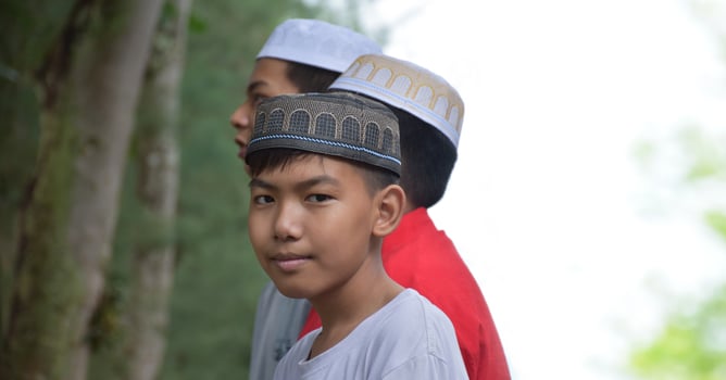 Portrait asian muslim or islamic boys standing together in front of tree and waiting to do the religious activity at school, soft and selective focus. photo