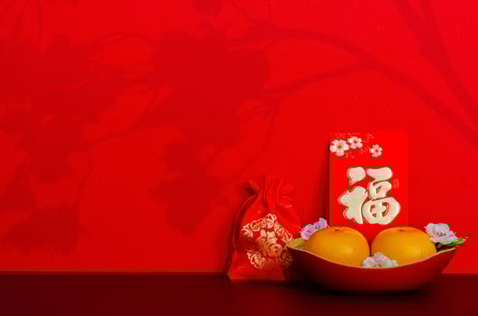 Red envelope packet or ang bao word mean wealth puts with oranges and red bag word is wealth with shadow of peach blossom on red glitter paper background. photo