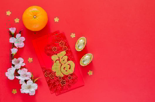 Red envelope packets or ang bao word means wealth with gold ingots, orange and Chinese blossom flowers for Chinese new year on red background. photo