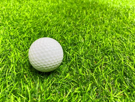 Golf ball close up on green grass on blurred beautiful landscape of golf course with sunrise,sunset time on background.Concept international sport that rely on precision skills for health relaxation. photo