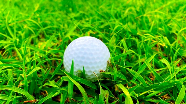 Golf ball close up on green grass on blurred beautiful landscape of golf course with sunrise,sunset time on background.Concept international sport that rely on precision skills for health relaxation. photo