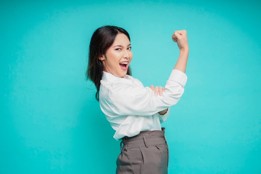 Excited Asian woman wearing a white shirt showing strong gesture by lifting her arms and muscles smiling proudly photo