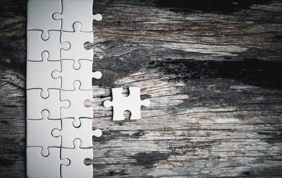 White details of jigsaw puzzle piece on wooden background. Concept of working together as a business team. The idea of getting involved, working for success. photo
