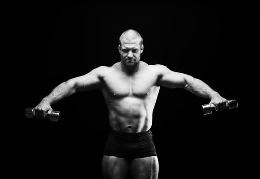 sports man standing on a black background, doing sports photo
