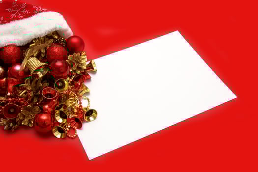Christmas toys spill out of santa's hat, next to an empty white sheet on a red background, copyspace, christmas content photo