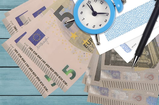 5 euro bills and alarm clock with pen and envelopes. Tax season concept, payment deadline for credit or loan. Financial operations using postal service photo
