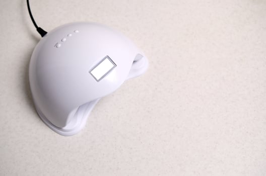 UV LED nail lamp for curing process by gel method lies on white table photo