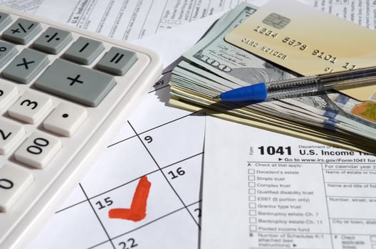 1041 Income Tax Return for Estates and Trusts blank with dollar bills, calculator and pen on calendar page with marked 15th April photo