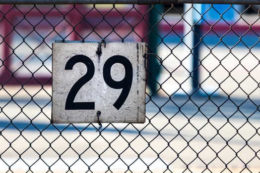 white sign on a chain link fence with the number 29 photo