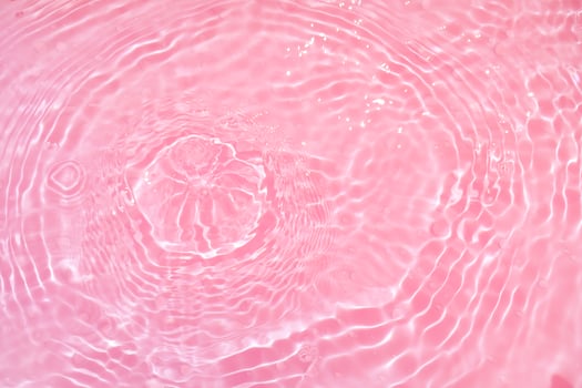 Defocus blurred transparent pink colored clear calm water surface texture with splashes and bubbles. Trendy abstract nature background. Water waves in sunlight with copy space. Pink watercolor shining photo