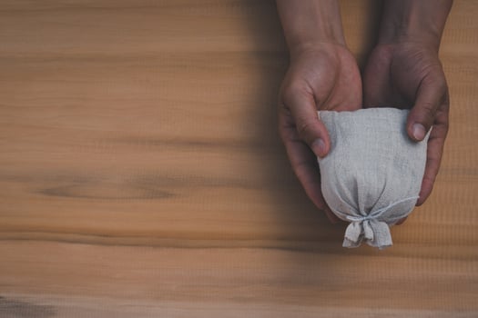 Top view of hands holding money bag on the wooden table background photo
