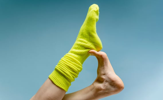 Woman with beautiful legs wears green socks on her feet. Isolated on blue background photo