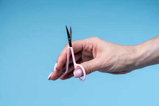 female hand holding scissors isolated on  blue background photo