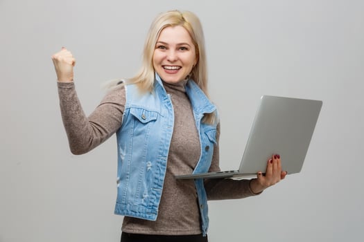 Happy young woman using laptop on gray background photo