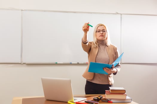 Portrait of pretty teacher holding notepads in a classroom in school photo