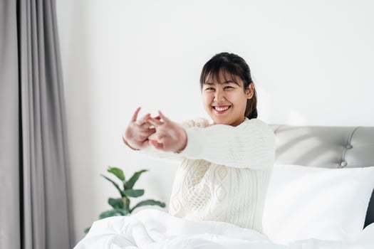 Happy Woman stretching her arms on the bed in the morning. photo
