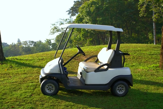 White golf cart parked on the golf course with morning sunlight photo