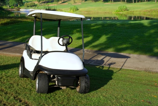 White golf cart parked on the golf course with morning sunlight photo