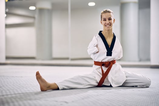 Happy female martial arts athlete with disability warming up while exercising taekwondo in health club. photo