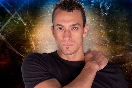 A very sexy and handsome male model poses for a studio portrait with a futuristic background and spot lighting. photo