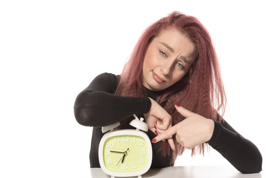 worried young woman holding alarm clock in her hand photo