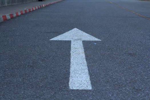 white arrow traffic sign on black asphalt on the road is a straight forward symbol used throughout the world. photo