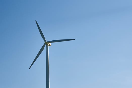Wind turbine against blue sky. Wind power energy concept photo