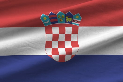 Croatia flag with big folds waving close up under the studio light indoors. The official symbols and colors in banner photo