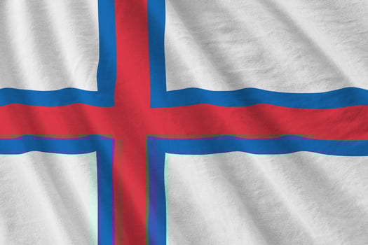 Faroe islands flag with big folds waving close up under the studio light indoors. The official symbols and colors in banner photo