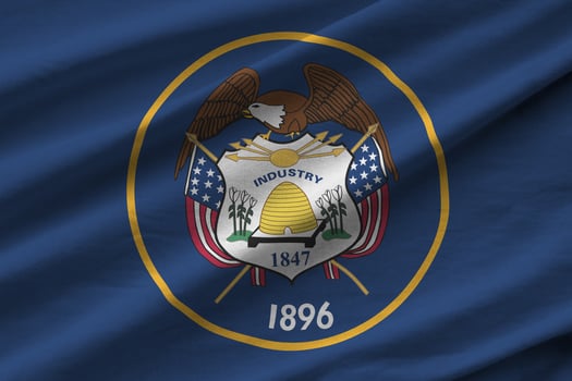 Utah US state flag with big folds waving close up under the studio light indoors. The official symbols and colors in banner photo