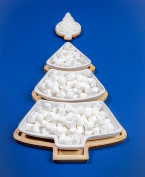 Plate in shape of Xmas tree with white marshmallows and white glazed gingerbread on top on blue. photo