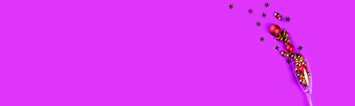 Purple web banner with with golden and red christmas balls in a wine glass. photo