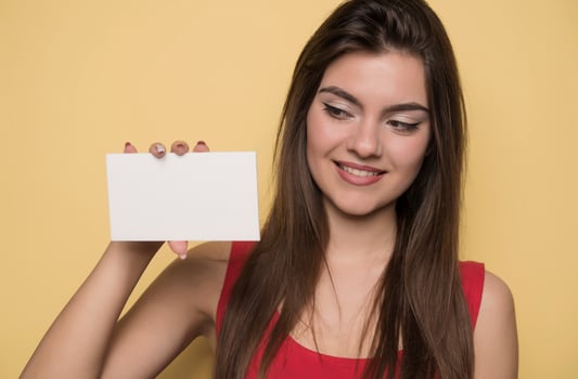 young smiling woman holding a blank sheet of paper for advertising photo