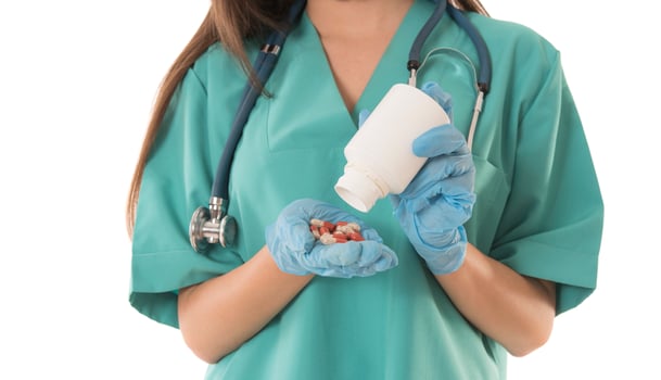 Portrait of professional female smiling doctor in green scrubs holding a brown pill bottle Medical Care photo