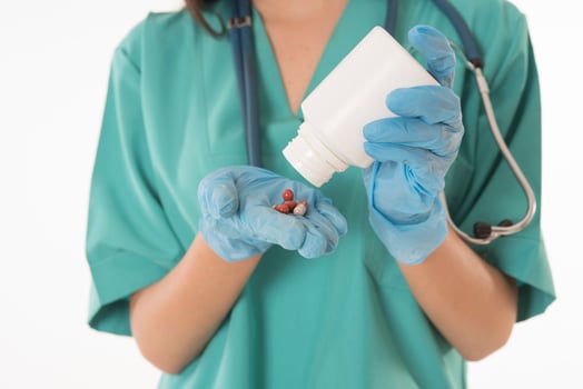 Portrait of professional female smiling doctor in green scrubs holding a brown pill bottle Medical Care photo