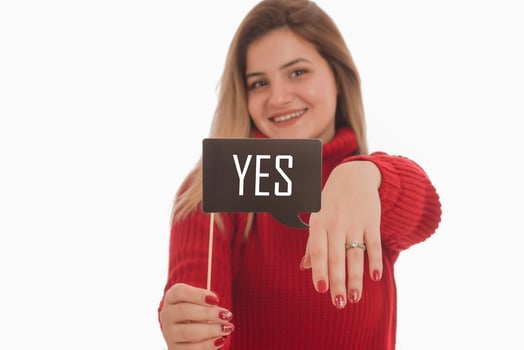 Woman holding engagement ring and sign saying YES photo