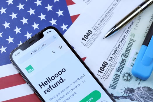 KHARKOV, UKRAINE - MARCH 5, 2021 HR Block website on iPhone 12 pro screen with 1040 and w-2 paper tax forms on US flag photo