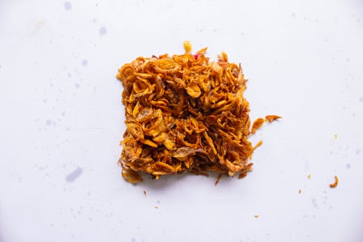 bawang goreng or Pile of fried Indonesian Deep Onion fries or shallots with circle shape isolated on white background. photo