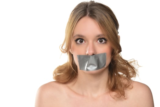 scared young woman with tape over her mouth. photo