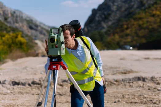 Surveyor engineer is measuring level on construction site. Surveyors ensure precise measurements before undertaking large construction projects. photo